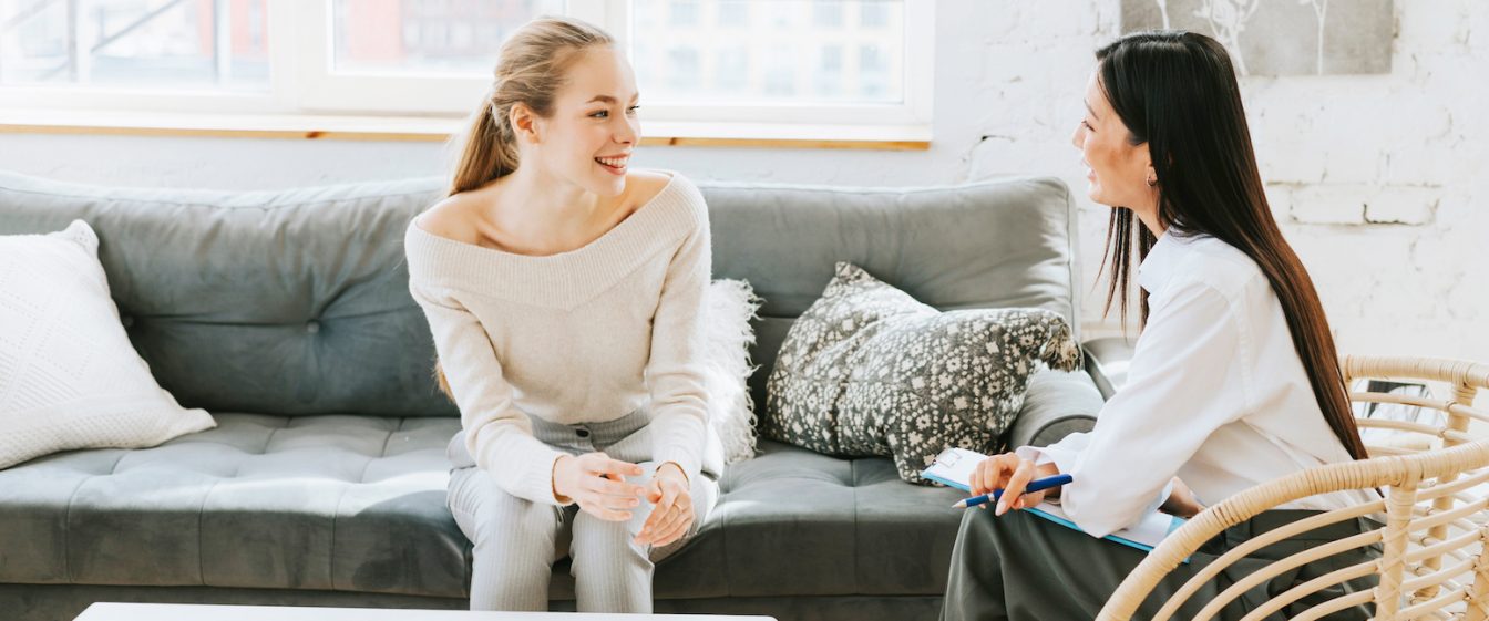 two happy looking women on a sofa in a coaching session