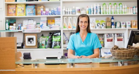 A veterinary receptionist sat in front a large range of foods and treatments.